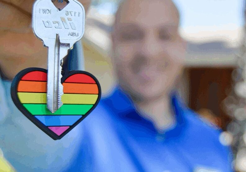 A man holding up a key to his home.